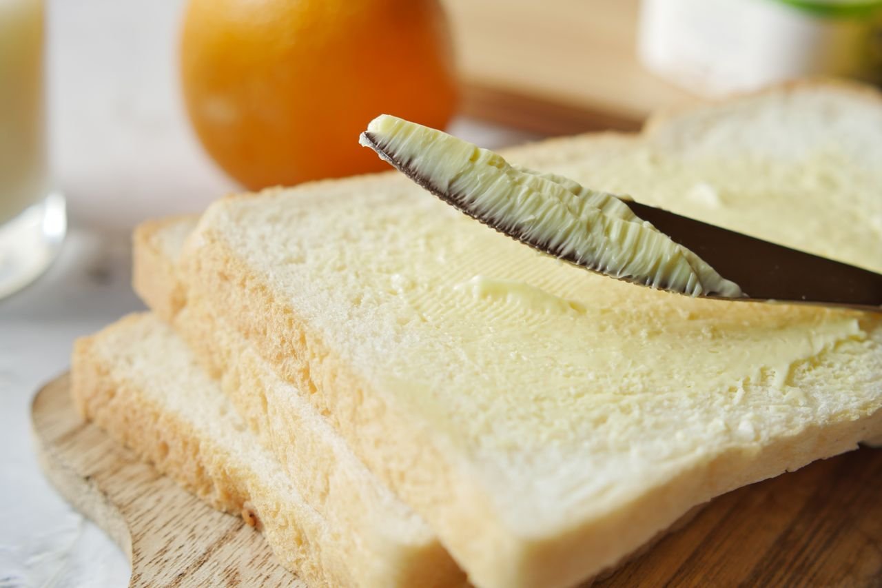 A close-up view of butter being spread on a slice of bread, perfect for breakfast scenes.